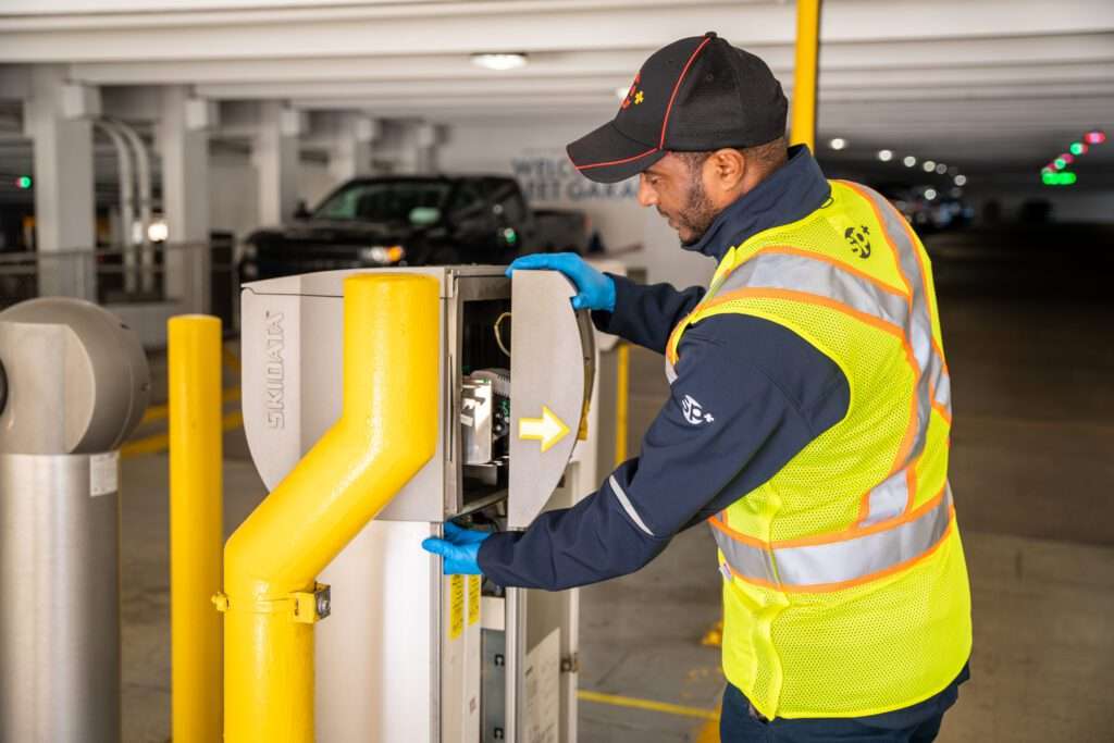 SP+ trabajador de mantenimiento de instalaciones arreglando equipos de aparcamiento
