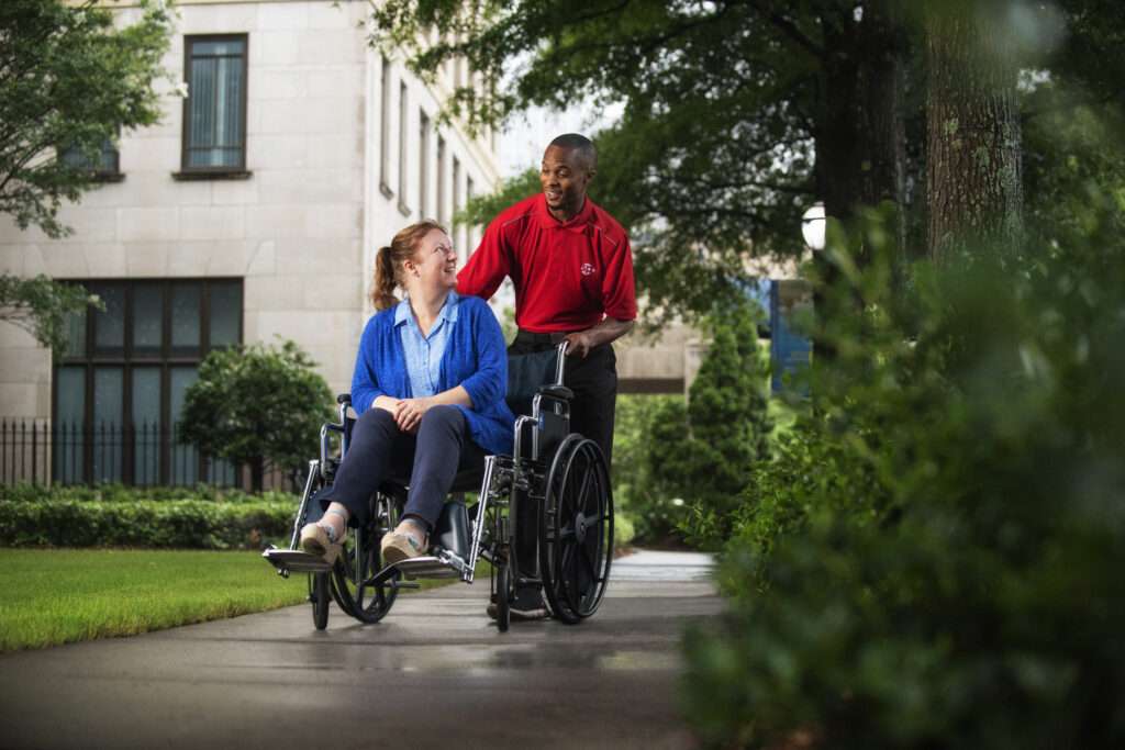 Employé SP+ poussant une dame en fauteuil roulant